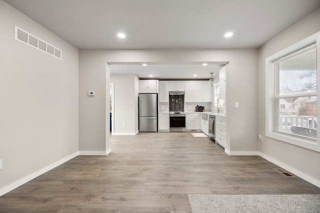 kitchen featuring tasteful backsplash, appliances with stainless steel finishes, light wood-type flooring, and white cabinets