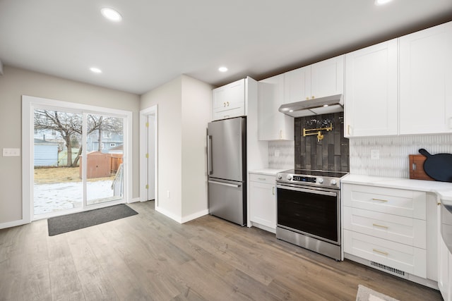 kitchen featuring appliances with stainless steel finishes, light hardwood / wood-style floors, decorative backsplash, and white cabinets