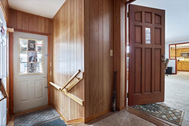 foyer entrance featuring light carpet and wooden walls