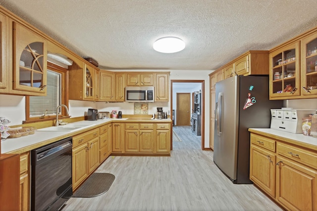 kitchen featuring sink, stainless steel appliances, a textured ceiling, and light wood-type flooring