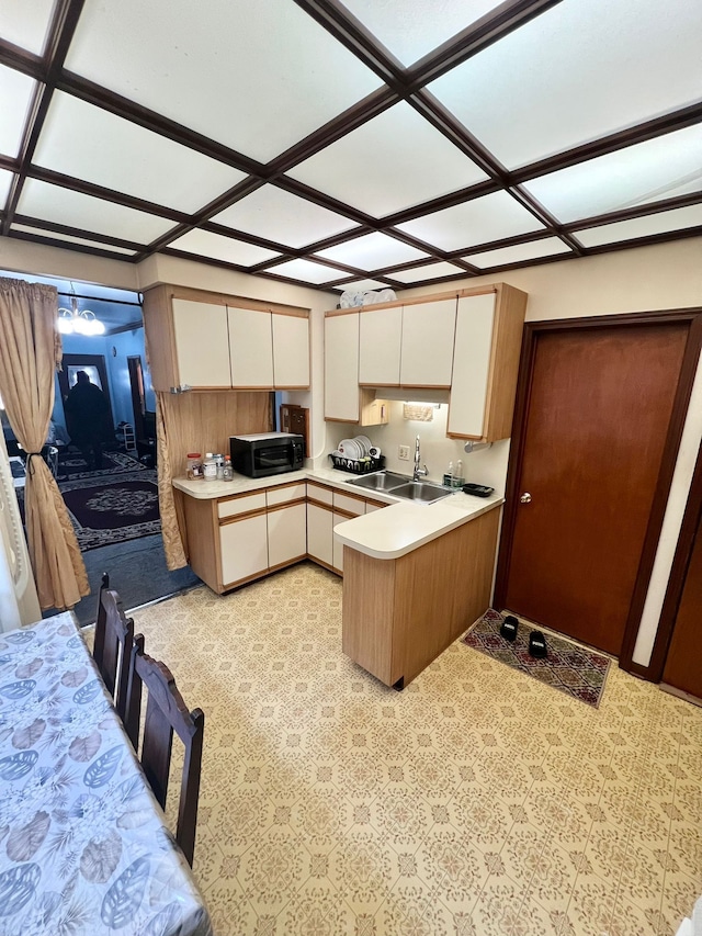 kitchen with cream cabinets, sink, and kitchen peninsula