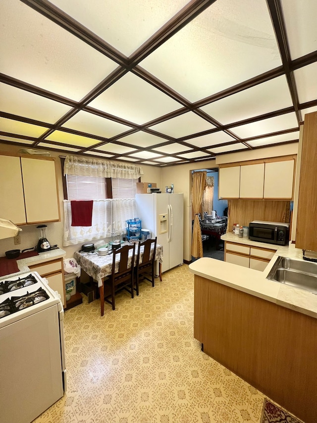 kitchen featuring white appliances, kitchen peninsula, and sink