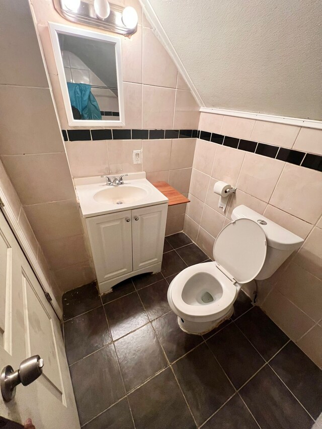 bathroom featuring vanity, tile patterned floors, tile walls, and toilet