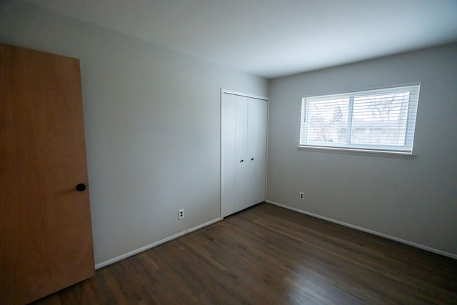 unfurnished bedroom with dark hardwood / wood-style floors and a closet