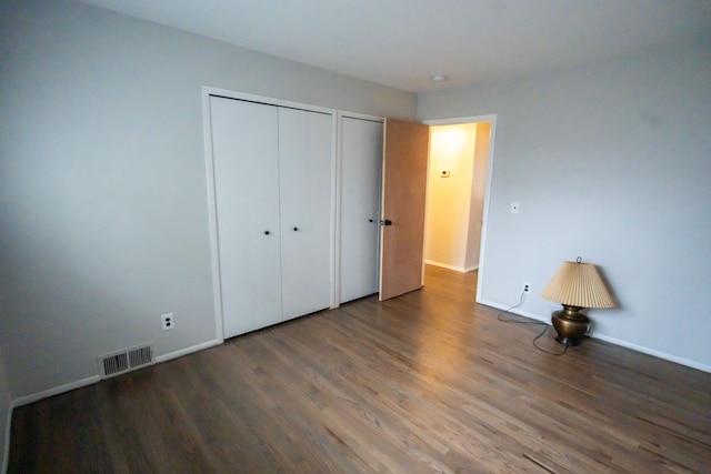 unfurnished bedroom featuring hardwood / wood-style flooring and multiple closets