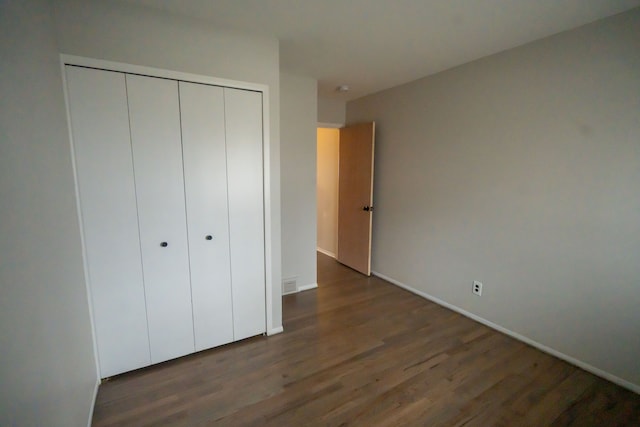 unfurnished bedroom featuring dark hardwood / wood-style floors and a closet