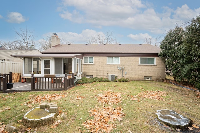 back of property with central AC unit, a yard, and a sunroom