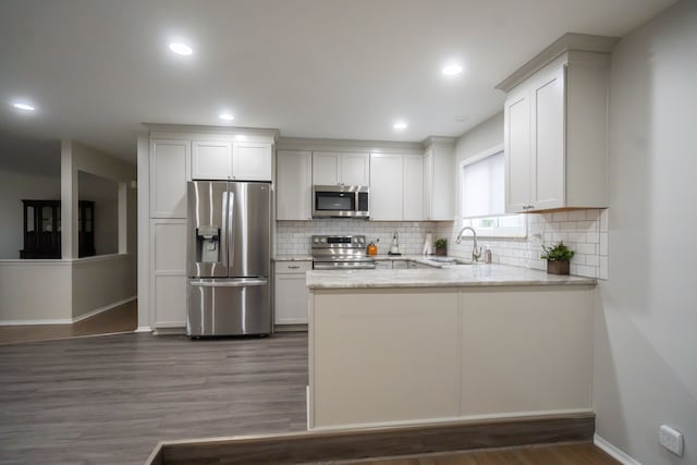 kitchen with dark hardwood / wood-style floors, sink, white cabinets, stainless steel appliances, and light stone countertops