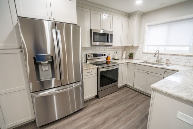 kitchen featuring stainless steel appliances, light stone countertops, sink, and white cabinets