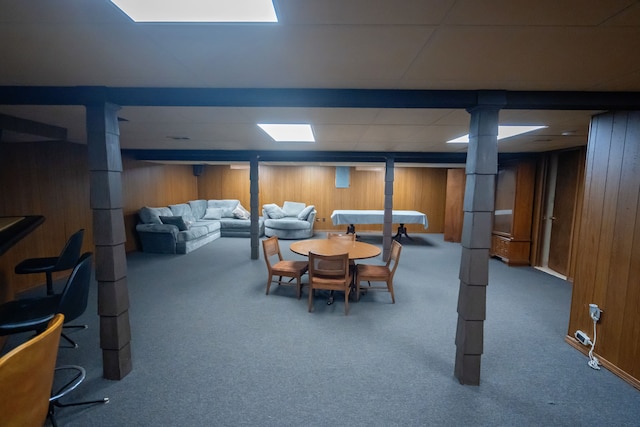 dining room with carpet flooring, wooden walls, and a drop ceiling