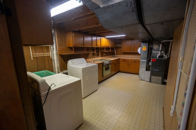 laundry area with washing machine and dryer and wood walls