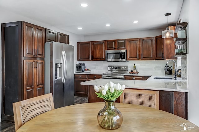 kitchen featuring sink, decorative light fixtures, appliances with stainless steel finishes, kitchen peninsula, and decorative backsplash