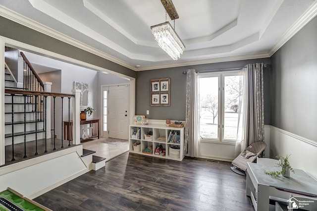 entrance foyer featuring dark hardwood / wood-style floors, ornamental molding, a tray ceiling, and a notable chandelier