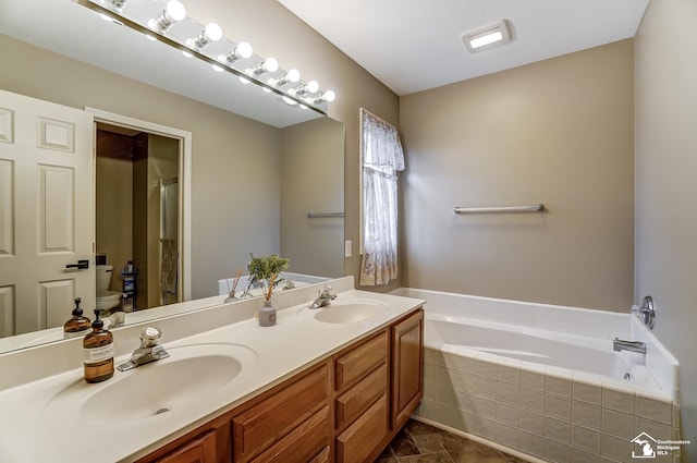 bathroom with vanity, tiled bath, and toilet