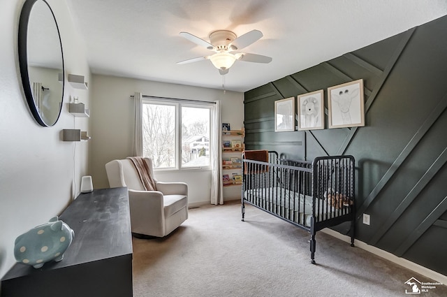 carpeted bedroom featuring a nursery area and ceiling fan