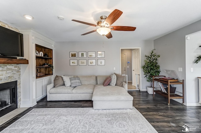 living room featuring dark hardwood / wood-style flooring, a fireplace, built in features, and ceiling fan