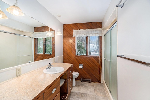 bathroom featuring vanity, a wealth of natural light, an enclosed shower, and wooden walls