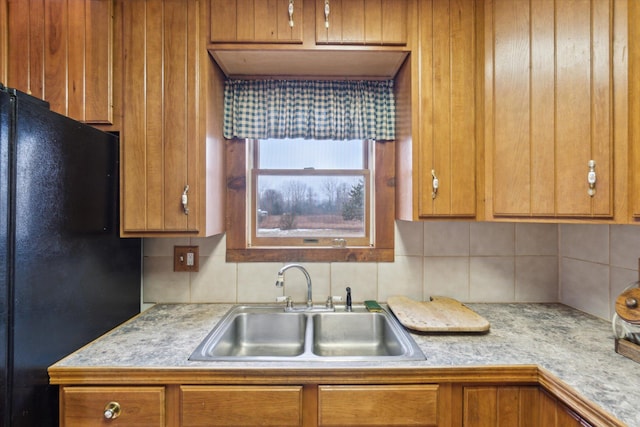 kitchen featuring black refrigerator, sink, and tasteful backsplash