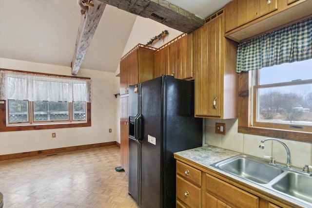 kitchen featuring vaulted ceiling with beams, black refrigerator with ice dispenser, sink, and light parquet floors