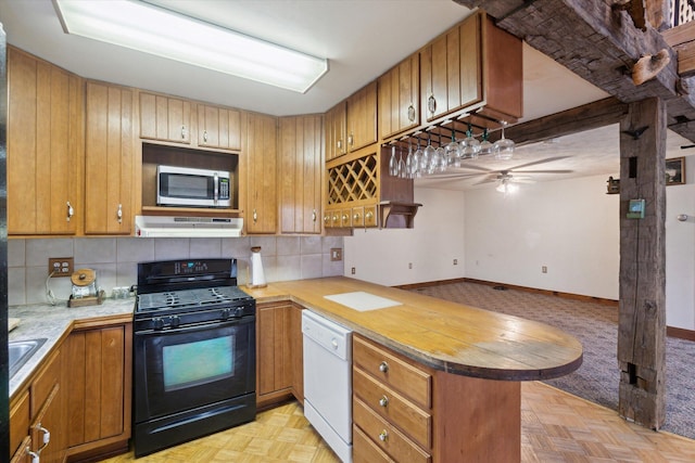 kitchen featuring black gas range, backsplash, white dishwasher, kitchen peninsula, and light parquet flooring