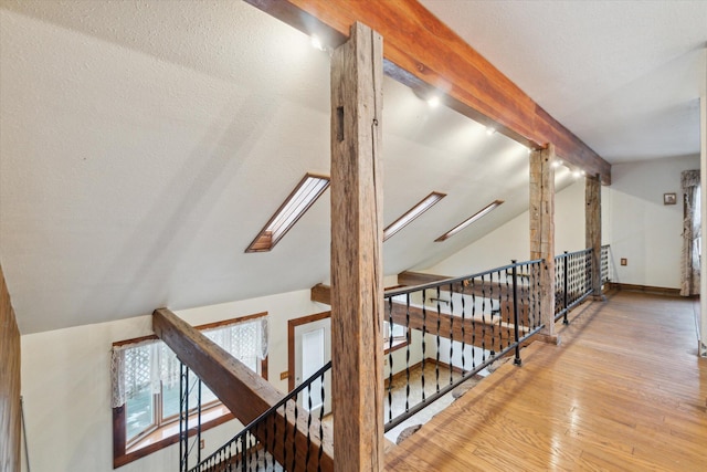 hallway featuring lofted ceiling with skylight and light hardwood / wood-style flooring