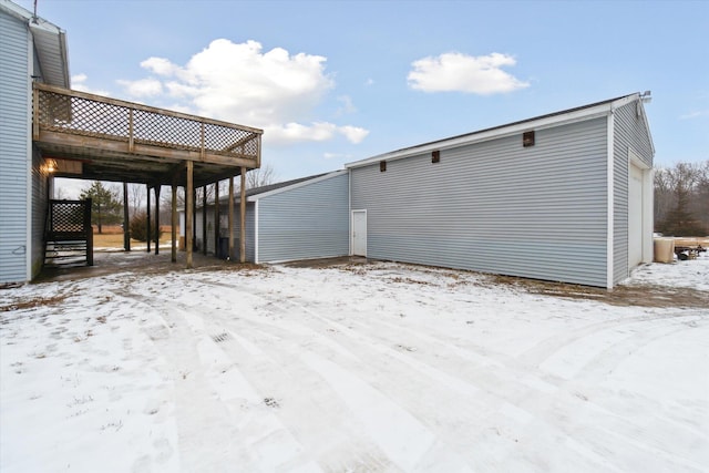 snow covered property featuring a wooden deck and a garage