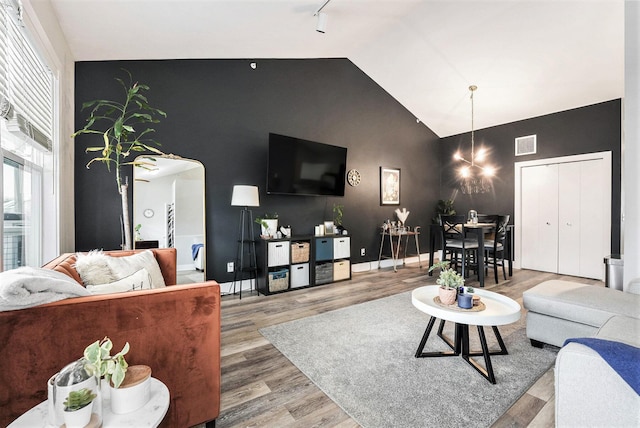 living room with rail lighting, a chandelier, hardwood / wood-style floors, and high vaulted ceiling