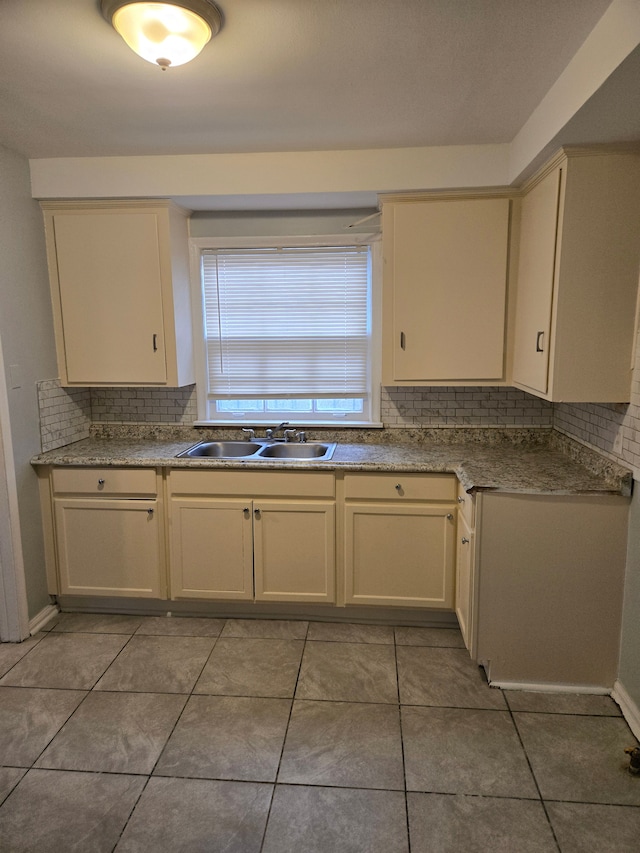 kitchen featuring tasteful backsplash, sink, light tile patterned floors, and cream cabinetry