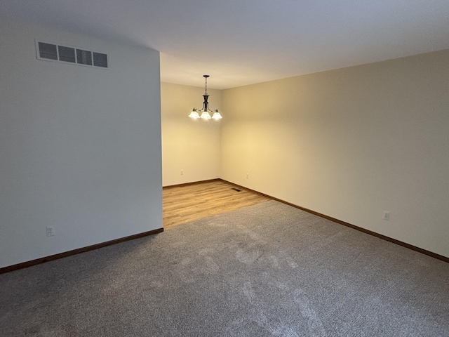 empty room featuring light carpet and a notable chandelier