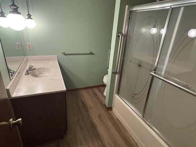 full bathroom featuring enclosed tub / shower combo, wood-type flooring, vanity, and toilet