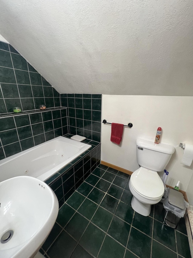 bathroom featuring sink, tile patterned flooring, toilet, tiled tub, and a textured ceiling