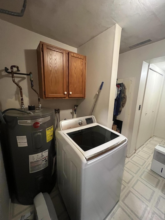 laundry area featuring water heater, washer / dryer, and cabinets