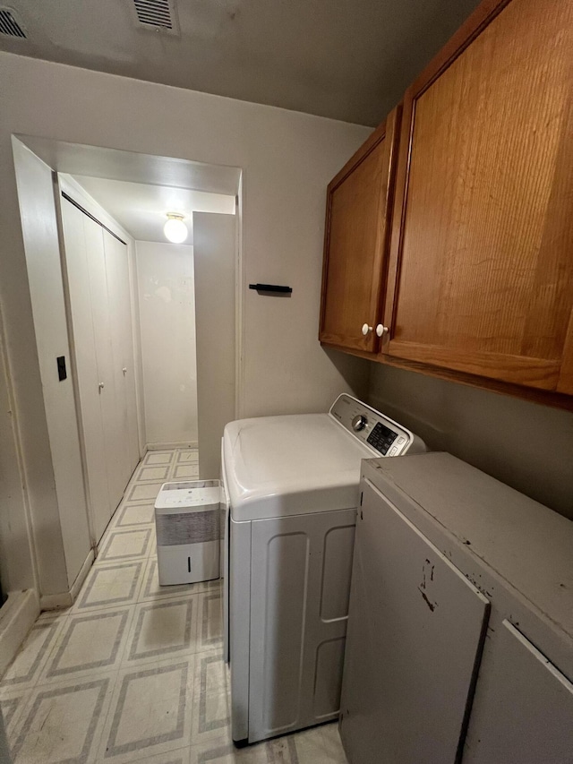 clothes washing area featuring cabinets and washer and clothes dryer