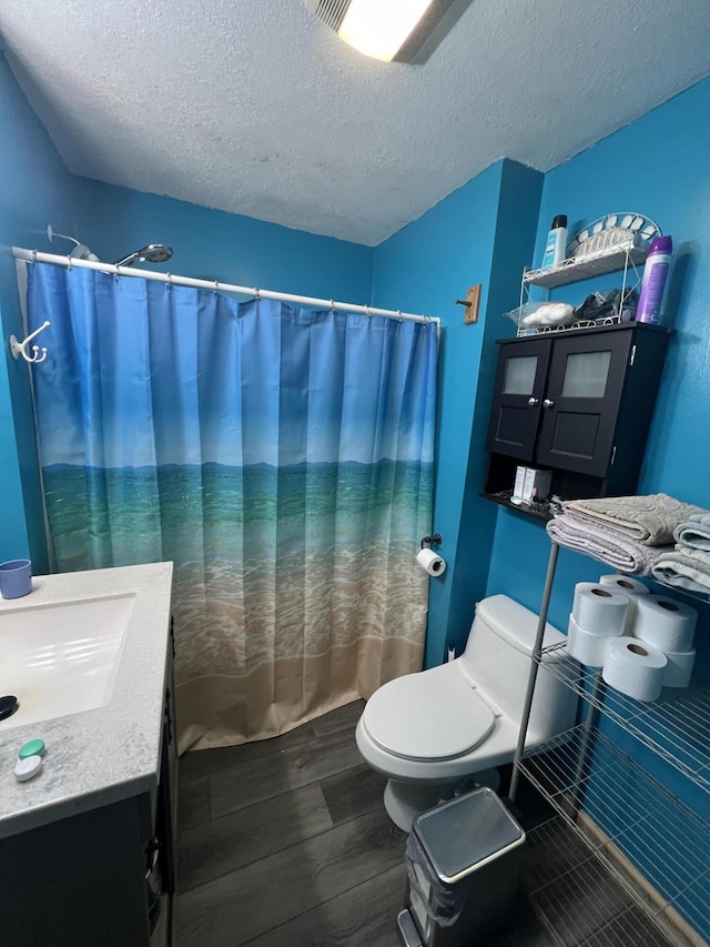 bathroom featuring toilet, wood-type flooring, a textured ceiling, vanity, and a shower with shower curtain