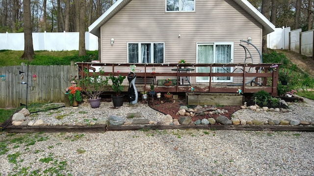 rear view of house featuring fence and a deck