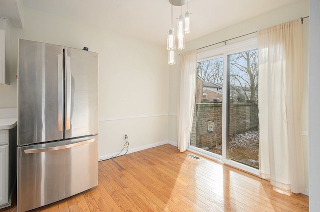 kitchen featuring hanging light fixtures, stainless steel refrigerator, and light hardwood / wood-style floors