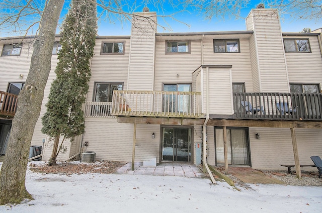 snow covered rear of property featuring a balcony and central air condition unit