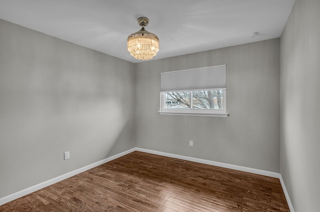 spare room featuring hardwood / wood-style flooring and a notable chandelier