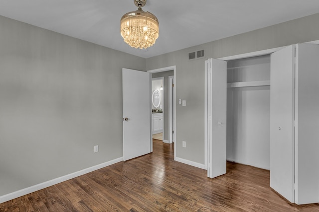 unfurnished bedroom featuring dark hardwood / wood-style floors, a closet, and a notable chandelier