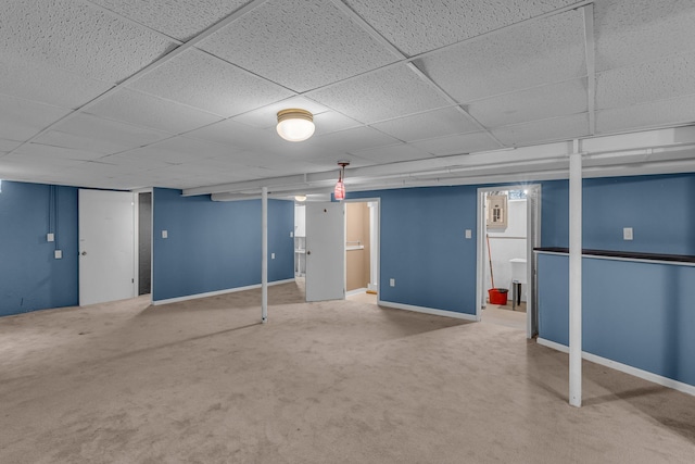 basement with a paneled ceiling and carpet