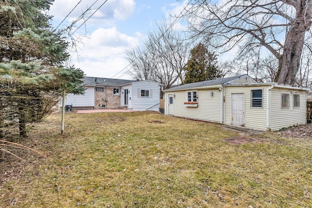 rear view of house with a patio, an outbuilding, and a lawn