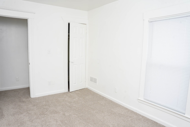 unfurnished bedroom with light colored carpet and a closet