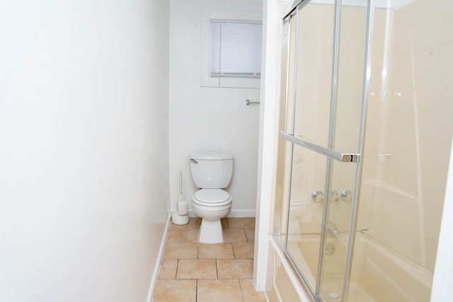 bathroom featuring tile patterned flooring, bath / shower combo with glass door, and toilet