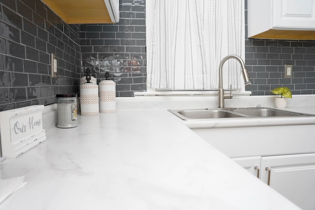 kitchen with white cabinetry, sink, and backsplash