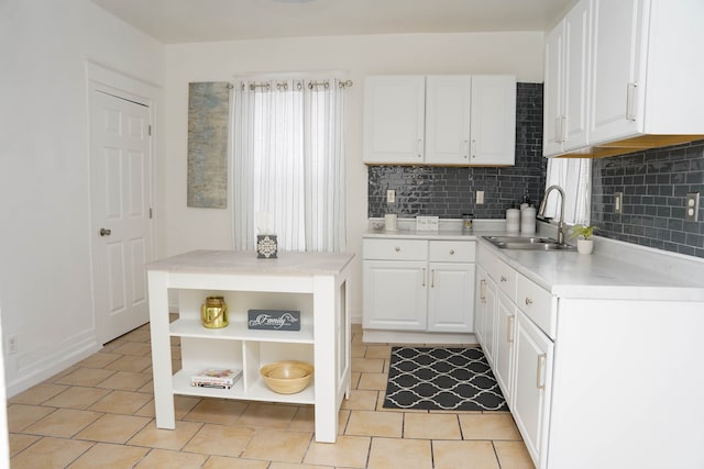 kitchen with white cabinetry, light tile patterned flooring, sink, and decorative backsplash