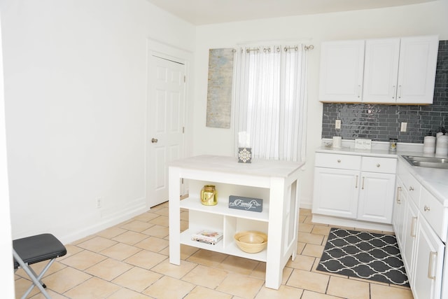 kitchen with light tile patterned flooring, white cabinets, and decorative backsplash