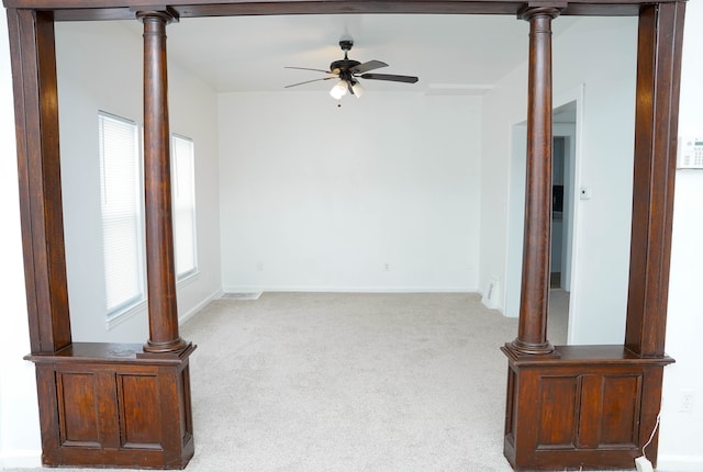 unfurnished living room with light colored carpet, decorative columns, and ceiling fan