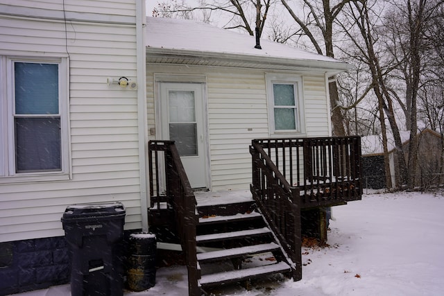 snow covered property entrance with a deck