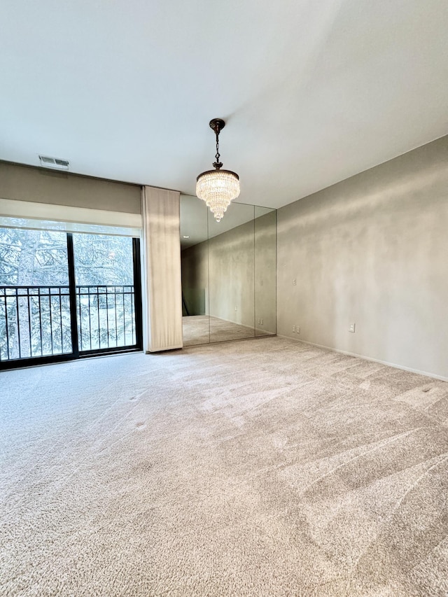 carpeted spare room featuring a chandelier