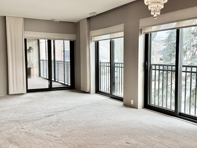 spare room featuring light carpet and an inviting chandelier